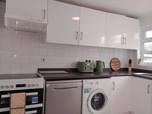 a white kitchen with a washing machine in it at 3BR House with garden near Bicester Village in Bicester