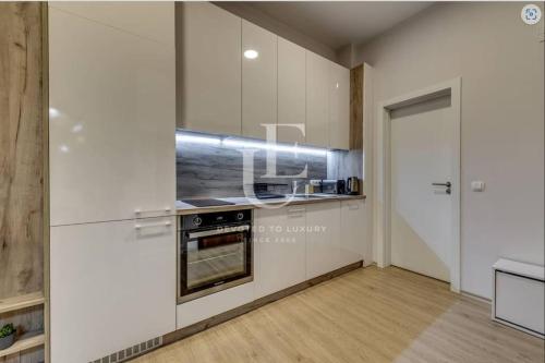 a kitchen with white cabinets and a stove at Geneva: A charming patio studio with private parking! in Sofia