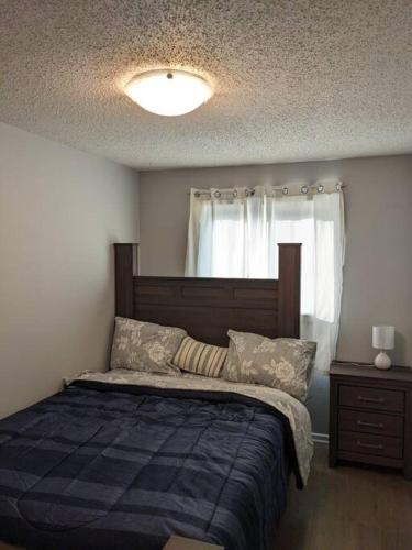 a bedroom with a bed with a blue blanket and a window at Bi-Level Suite in Saskatoon in Saskatoon