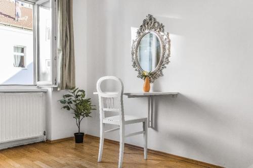une chaise blanche assise à côté d'une table avec miroir dans l'établissement Central 1BR Apt. Near The Danube & Prater Stern, à Vienne