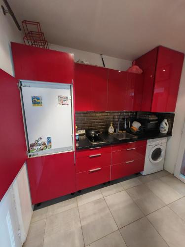 Il comprend une cuisine équipée de placards rouges et d'un réfrigérateur blanc. dans l'établissement Sean, à Issy-les-Moulineaux