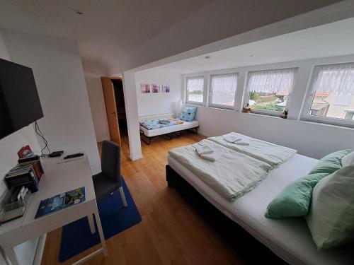 a bedroom with a bed and a desk and windows at Ferienwohnung-Vetter in Bodelshausen