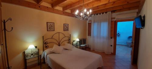 a bedroom with a large white bed and a chandelier at Casa Rural Forn del Sitjar in Cabanes