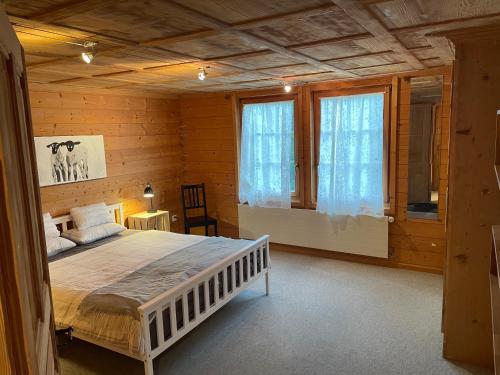 1 dormitorio con 1 cama blanca en una habitación de madera en Edelweiss 4 Zi Ferienwohnung in Landhaus, en Frutigen