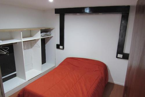 1 dormitorio con cama roja y ventana en De Raiz en Mar del Plata