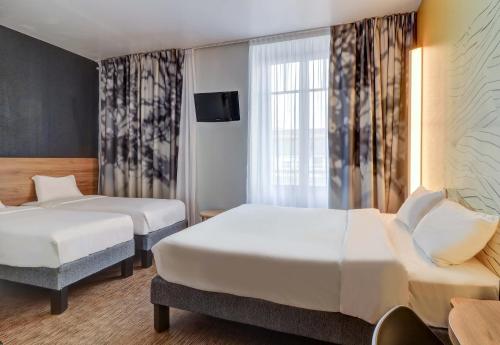 ディジョンにあるB&B HOTEL Dijon Centreのベッド2台とテレビが備わるホテルルームです。