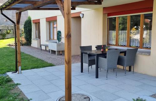 een patio met een tafel en stoelen onder een pergola bij Ruheort in Beinwil