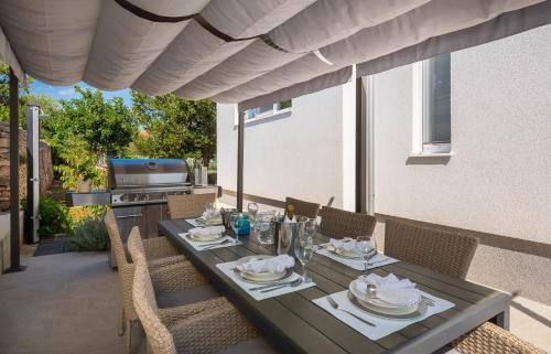 a table and chairs on a patio with a table and a stove at House Villa Z&Z in Seget Vranjica