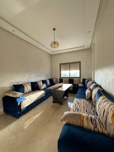a large living room with blue couches and a table at Apparemment de luxe Bouznika in Bouznika