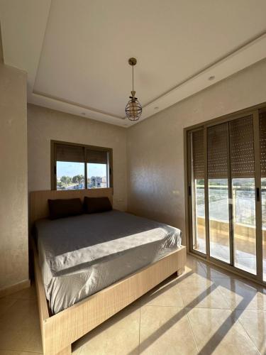 sypialnia z łóżkiem i dużym oknem w obiekcie Apparemment de luxe Bouznika w mieście Bouznika