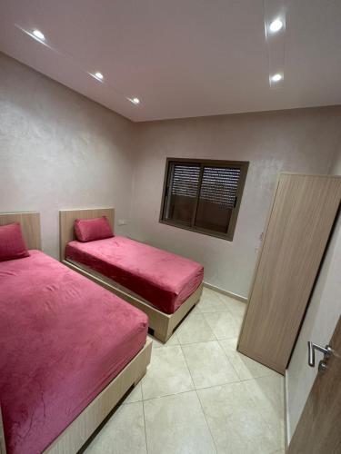a bedroom with two beds with pink sheets and a window at Apparemment de luxe Bouznika in Bouznika