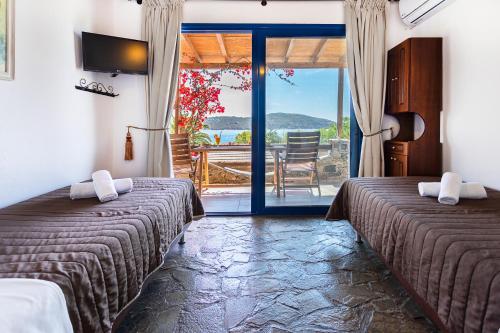 a room with two beds and a balcony with a view at Vassilia on the beach Serifos in Livadakia