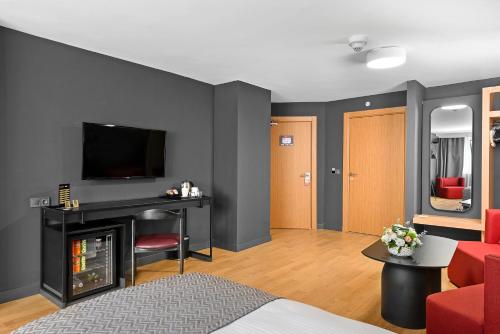 a living room with a bed and a television on a wall at İbos Hotels Izmir in Izmir