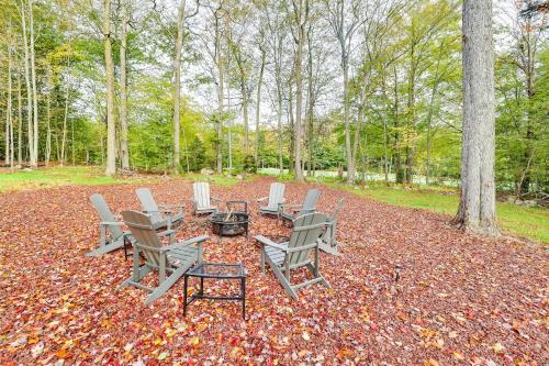 a group of chairs and a fire pit in the woods at Hot Tub and Lake Access Spacious Tobyhanna Home in Tobyhanna