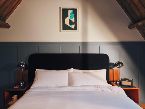 a bedroom with a white bed with a black headboard at The Hoxton, Lloyd Amsterdam in Amsterdam