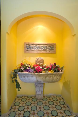a large flower arrangement in a room with a yellow wall at Hotel La Tonnarella in Sorrento
