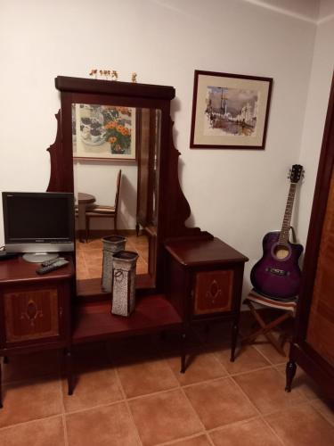 um quarto com um espelho e uma televisão e uma guitarra em Cal Manyo em Puigvert de Lérida