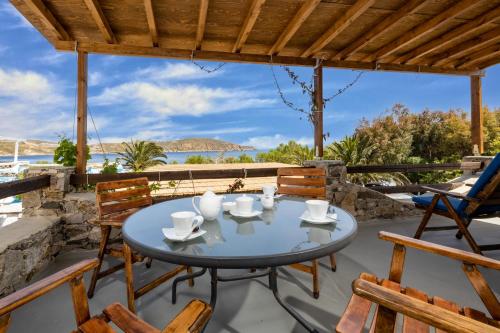 een patio met een tafel en stoelen en uitzicht op de oceaan bij Vassilia on the beach Serifos in Livadakia