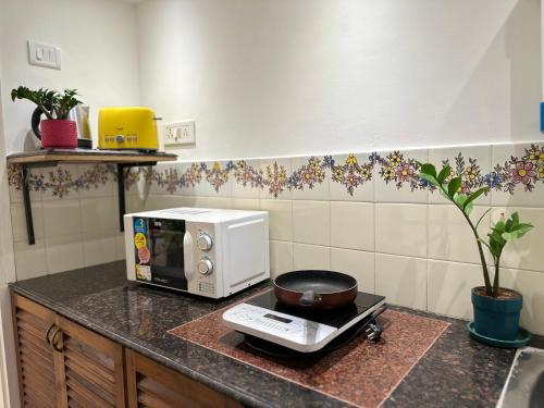 a kitchen counter with a microwave and a pan at Nestwood - By The Beach Goa in Benaulim