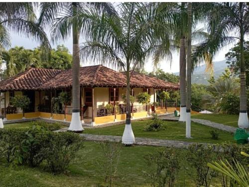 a house with palm trees in front of it at Hotel Campo Campestre La Coqueta in Santa Fe de Antioquia