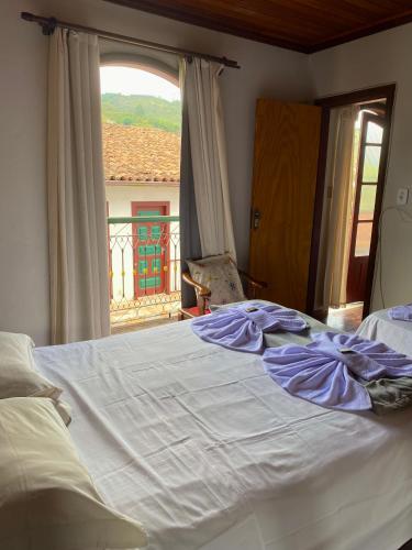 a large white bed in a bedroom with a window at Casa do Alferes in Ouro Preto