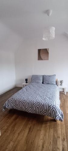a bedroom with a bed with a black and white comforter at Maël-Carhaix location Maison 4 chambres in Maël-Carhaix