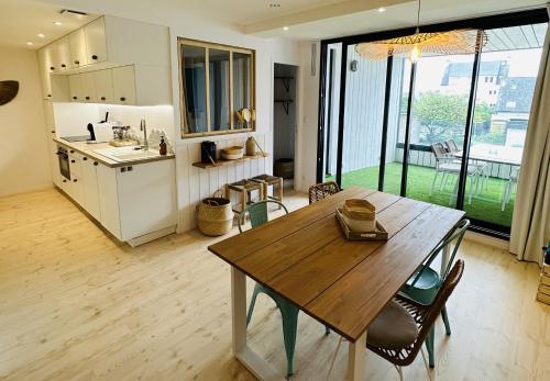 a kitchen and dining room with a wooden table at Appart'Hôtel & Spa "Les Voiles" Belle Île en Mer in Carnac