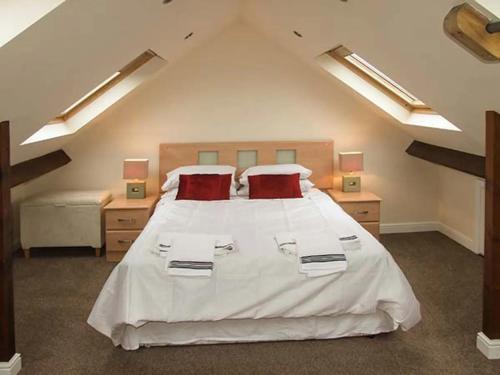 a bedroom with a large white bed with red pillows at Tonga Cottage 302 Over Lane in Belper