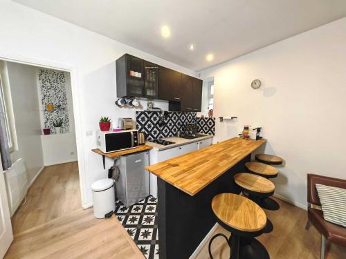- une cuisine avec un comptoir et quelques tabourets en bois dans l'établissement 3 Pièces à Saint-Ouen (Métro 13/14), à Saint-Ouen