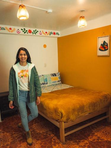 a woman standing next to a bed in a room at The Chusay Rooftop in Cusco