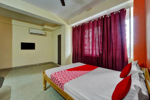 a bedroom with a bed and a window with red curtains at OYO Flagship Hotel CDS Regency in Patna