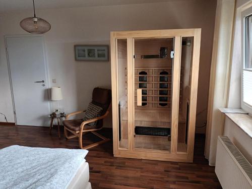 a bedroom with a wooden cabinet and a chair at Ferienwohnung Fackiner in Grüsen