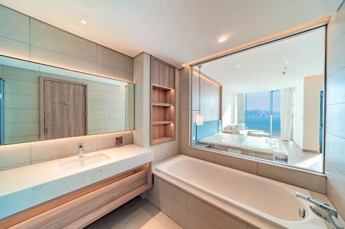 a bathroom with a tub and a sink and a large window at Căn hộ khách sạn Alacarte Hạ Long in Ha Long