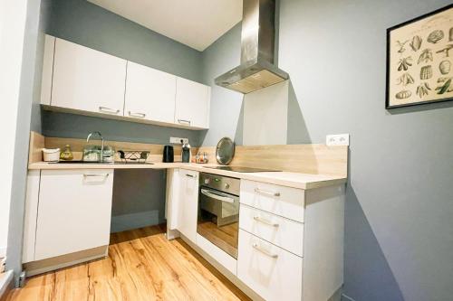 une petite cuisine avec des armoires blanches et une cuisinière dans l'établissement #B7 Le Rochambeau L'Aigle Vallier Libération, à Grenoble