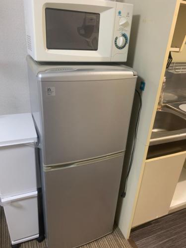 a microwave on top of a refrigerator in a kitchen at LIONS YONEGAHAMA l 米が浜通 in Yokosuka