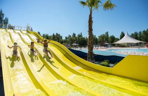 a group of people riding down a slide at a water park at MOBILHOME FABULEUX CAMPING VIAS PLAGE - PISCINE et SPA - 4 ETOILES in Vias