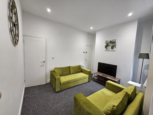 een woonkamer met twee groene banken en een televisie bij 16 Newcastle street by Prestige Properties Serviced Accommodation in Roose