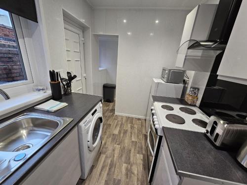 a small kitchen with a sink and a washing machine at 16 Newcastle street by Prestige Properties Serviced Accommodation in Roose