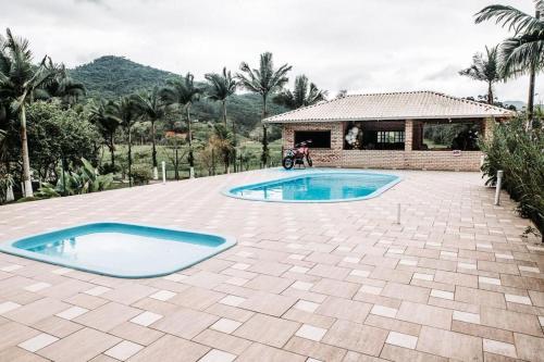 a swimming pool in a patio with a house at Fazenda Momm - Pousada e Eventos in Camboriú