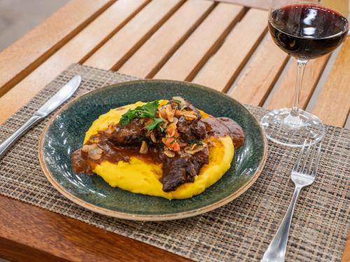 a plate of food on a table with a glass of wine at LP Los Portales Hotel Piura in Piura