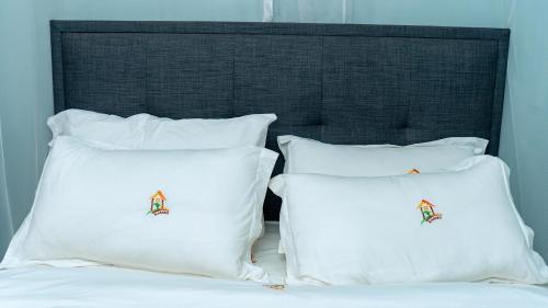 a bed with white pillows and a black headboard at Villa Karibu in Kampala