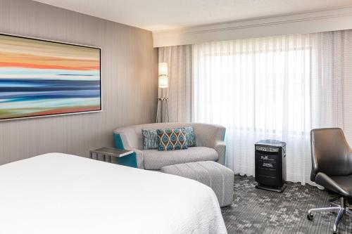 a hotel room with a bed and a chair at Courtyard by Marriott Columbus Tipton Lakes in Columbus