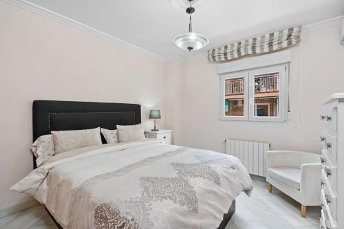 a white bedroom with a bed and a chair at PISO EN CALLE ARABIAL, JUNTO A EL CORTE INGLÉS in Granada