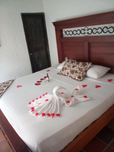 a bed with red rose pedals on it at hotel el quijote in La Pintada