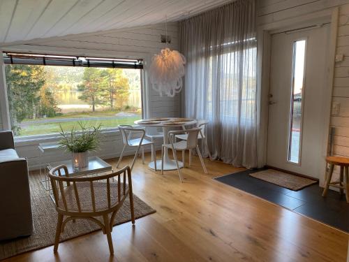 a living room with a table and chairs and a large window at Peaceful and Scandinavian-style Guesthouse with Scenic Nature and Seaview in Domsjö