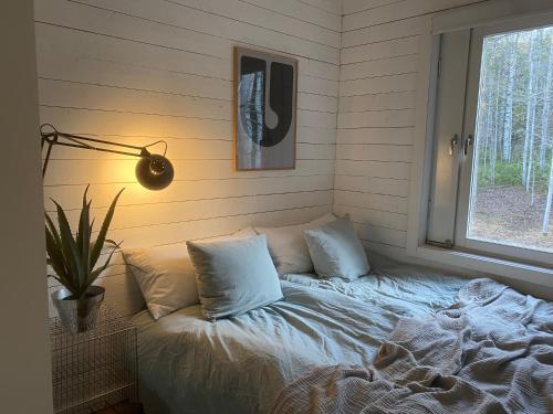 a bed with pillows in a room with a window at Peaceful and Scandinavian-style Guesthouse with Scenic Nature and Seaview in Domsjö