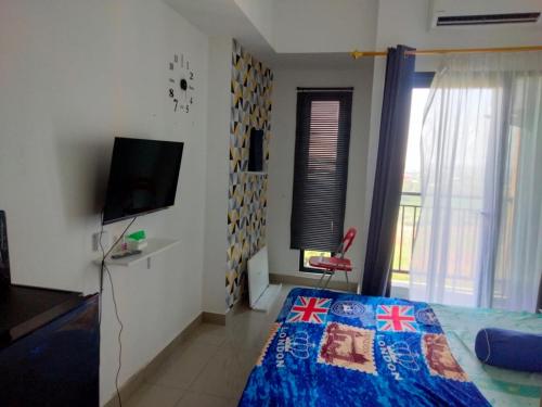 a bedroom with a bed and a flat screen tv at Studio Healing Sayana Apartment in Tambun-lobangbuaja