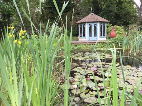 a garden with a gazebo and a pond at Fernwood in Ringwood