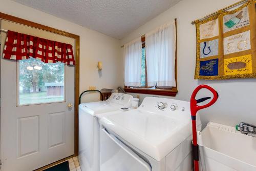 a laundry room with two white washers and a red mop at Grand Isle Lake House in Grand Isle
