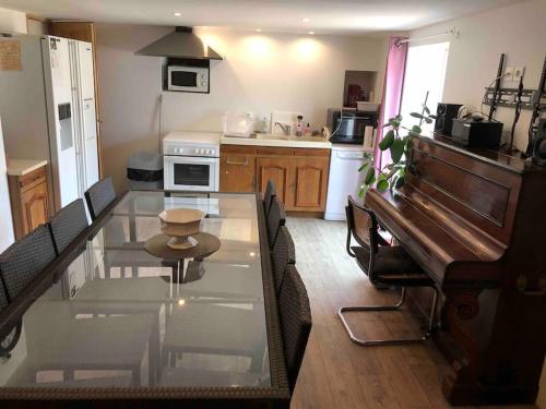 - une cuisine avec une table en verre, des chaises et un piano dans l'établissement Rez de maison jardin appart, à Saint-Pont